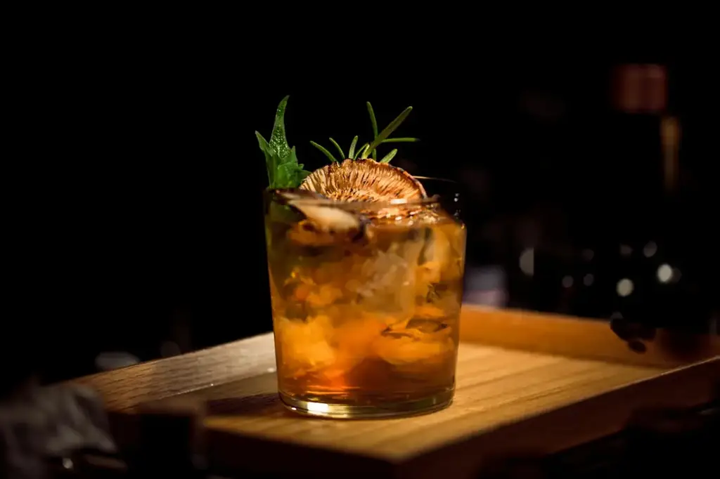 A house cocktail on the dark wood bar of the example restaurant